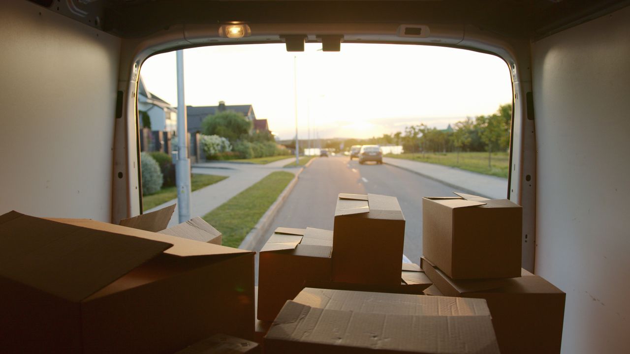 services-01 A scenic view from a delivery van loaded with cardboard boxes at sunset on a suburban street.